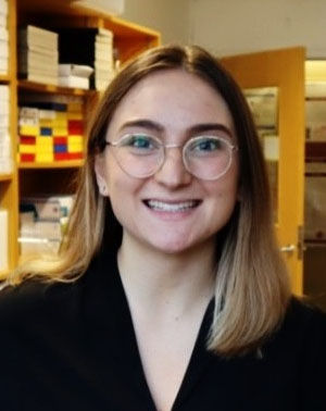 A picture of Celine. She is a young white woman wearing clear-framed 
											glasses. She is smiling.