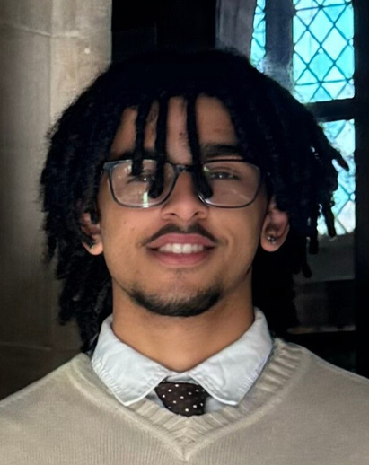 A photo of Lorenzo. He is a young Black man with glasses and is smiling.